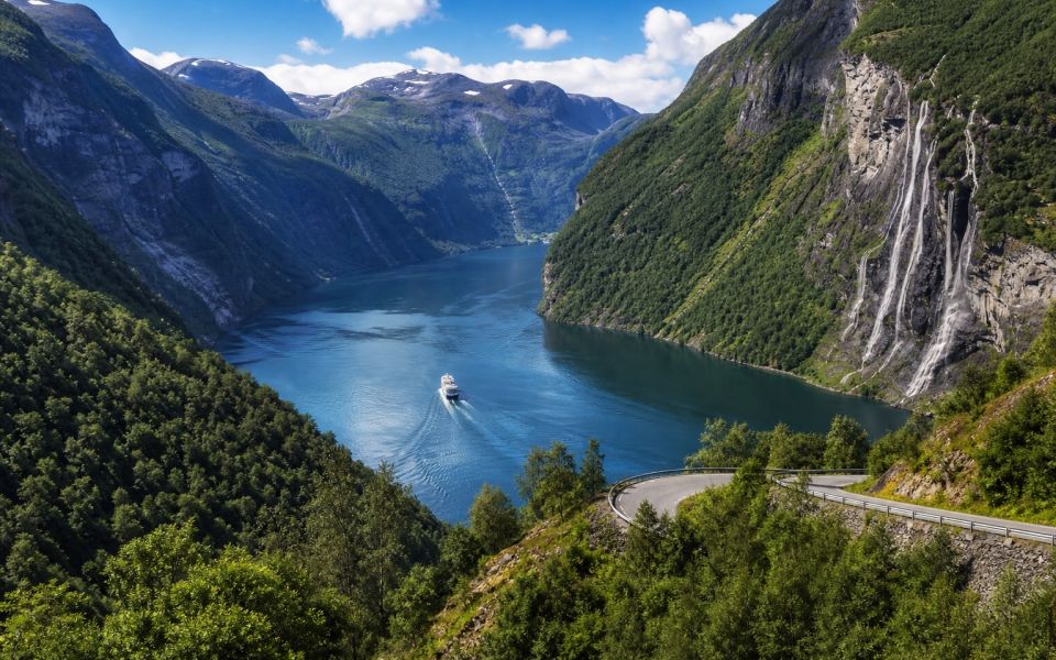 A deep Norwegian fjord, green mountains, waterfalls and a ferry
