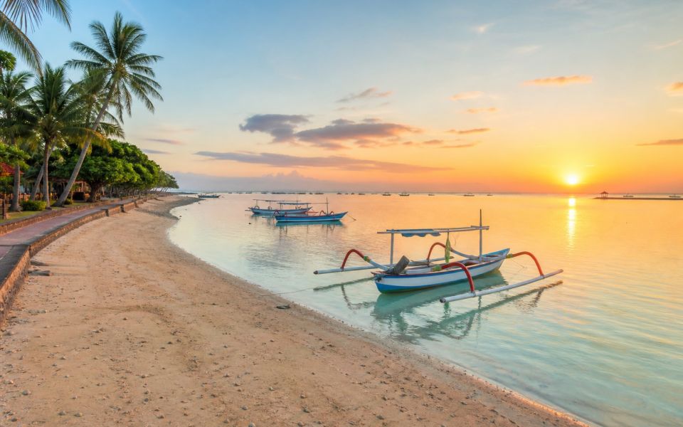 Sunrise, boats, and a tranquil coastal walkway at Sanur Beach in Bali