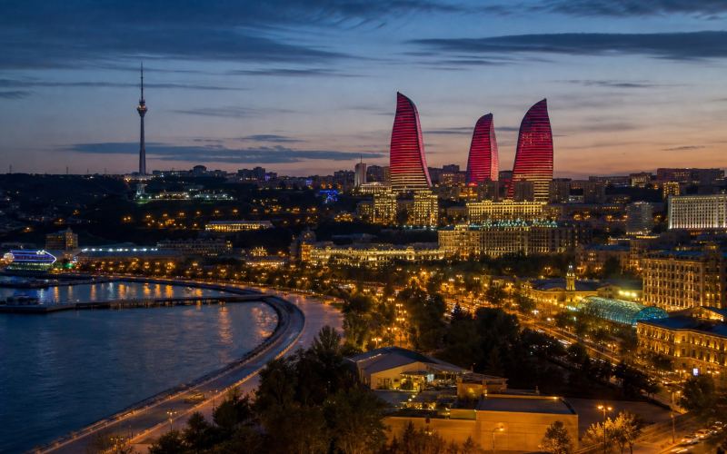 The lights of Baku, the Flame Towers, and the Caspian Sea embankment during blue hour
