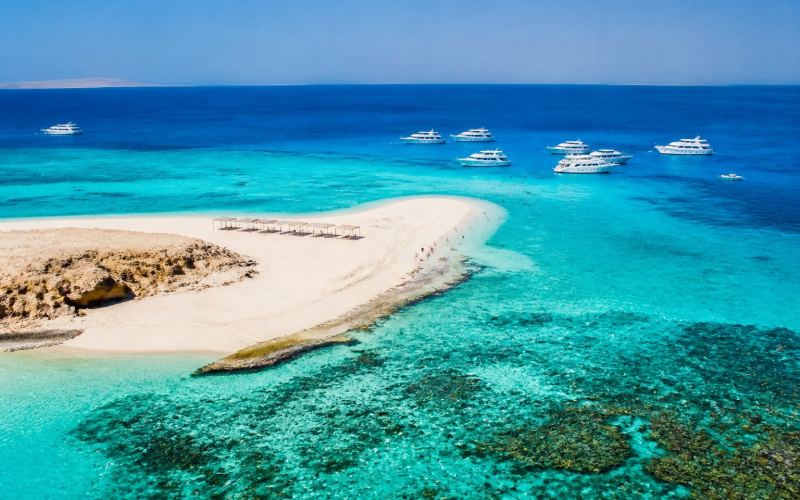 Белая песчаная коса, бирюзовое море и прогулочные лодки у островов Гифтун