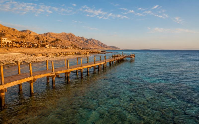 A pontoon, a clear reef, and desert mountains on the coast of Marsa Alam