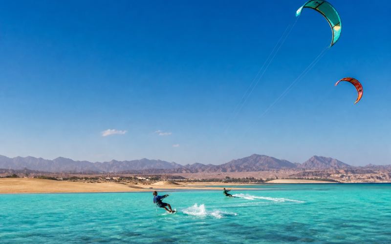 Kitesurfers in the turquoise lagoon of Soma Bay with desert mountains in the background