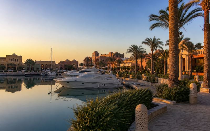 Yachts, palm trees, and sandy architecture of Soma Bay Marina at sunset