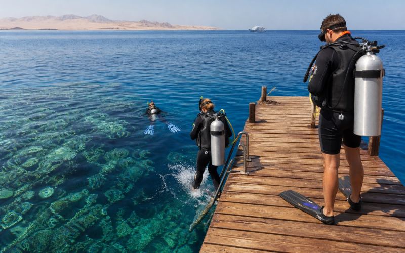 Divers enter the Red Sea from a pontoon at the Soma Bay house reef
