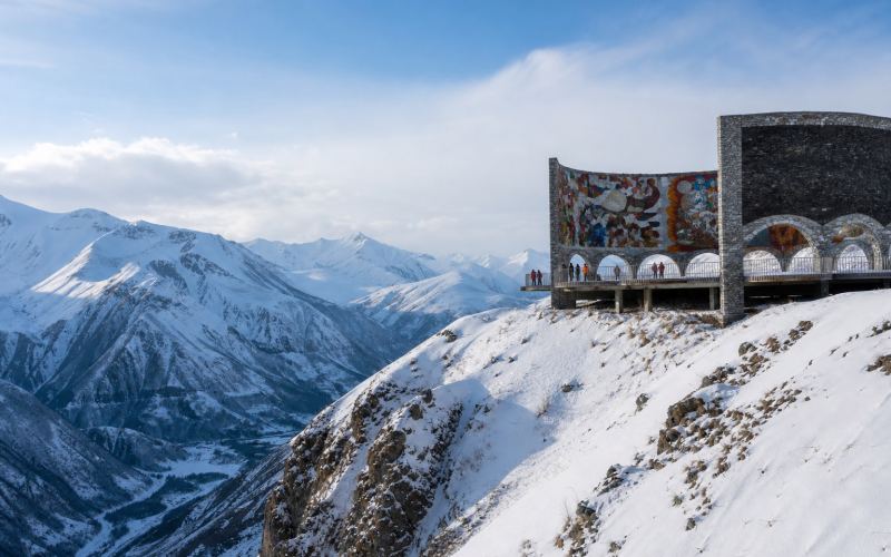 The Friendship of Nations Arch over a snowy valley near Gudauri
