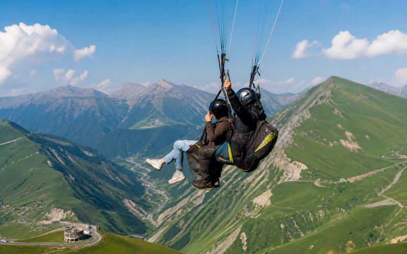 Tandem paragliding over the green mountain valleys of Gudauri in summer