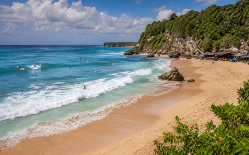 Limestone cliffs, golden sand, and surfing waves at Balangan Beach