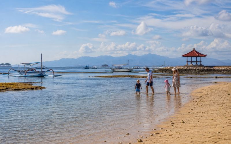 Families with children in the shallow, calm waters of sheltered Sanur Beach
