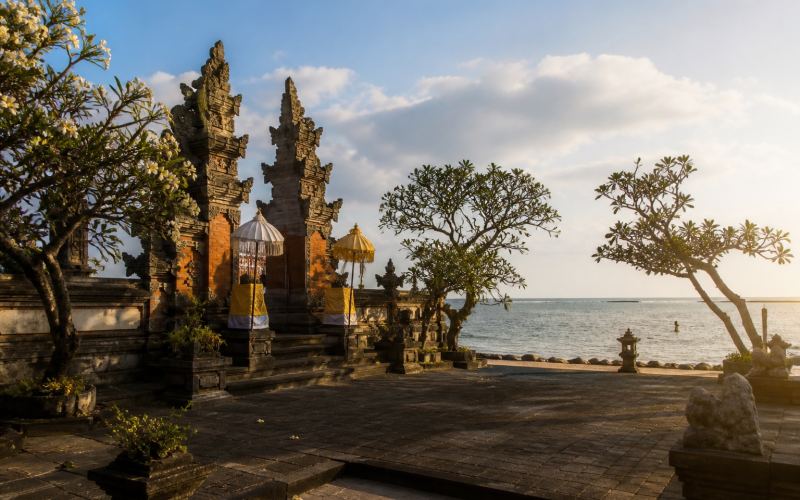 A Balinese temple courtyard with carved gates next to the sea in Sanur