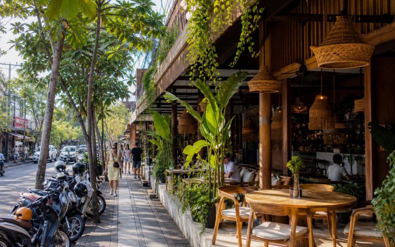 An outdoor cafe, tropical plants, and a bustling street in Seminyak