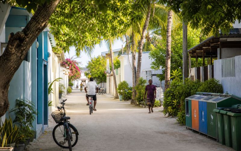 A shady street with bicycles and segregated containers on Ukulhas Island