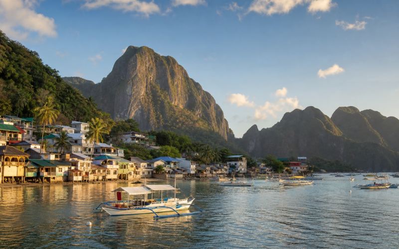 Boats in Bacuit Bay and the coastal village of El Nido with cliffs in the background