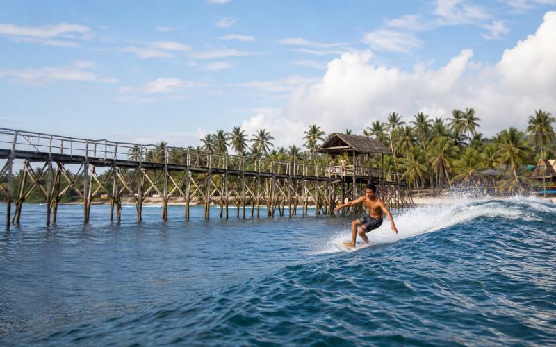 A surfer rides a wave at Cloud 9, a wooden pier on Siargao Island
